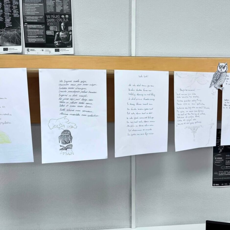 Pie korķa dēļa piestiprinātas piecas ar roku rakstītas lapas ar dzejoļiem un zīmējumiem. Redzami zīmējumi, piemēram, dzeltens saulriets, cilvēks lasa grāmatu, izgriezta pūce un zvans. Uz kreisās lapas ir virsraksts 