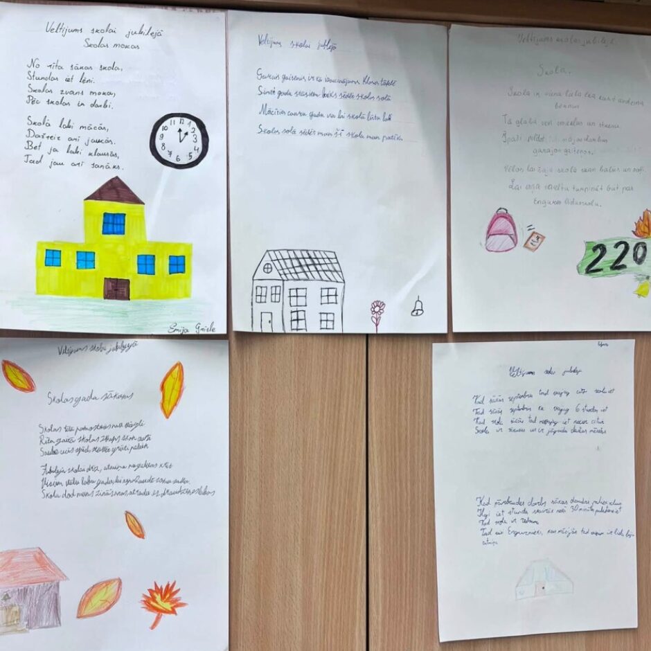 Bērnu zīmējumu un dzejoļu izstāde pie koka skapja durvīm. Darbos attēlotas dažādas skolas ēkas, pulkstenis, mugursoma un rudens lapas, atspoguļojot skolas dzīvi un tēmas. Vairākos darbos ir uzraksts 