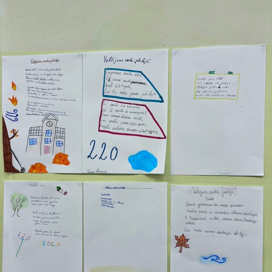 Sešas lapas ar bērnu zīmējumiem un rokraksta tekstiem, kas veltīti skolas jubilejai, piespraustas pie gaiši zaļas sienas. Lapās redzami tādi virsraksti kā 